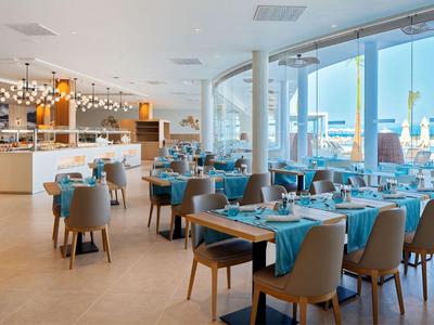 Restaurant moderne avec nappes bleues et grandes fenêtres donnant sur l'extérieur.