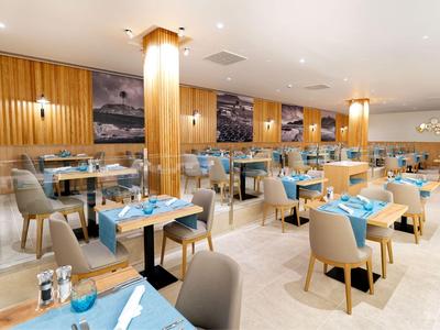 Restaurant moderne et lumineux avec des murs en bois et des tables dressées en bleu dans un hôtel.