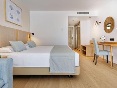 Chambre d'hôtel moderne avec lit double, bureau, chaise et sol en bois.