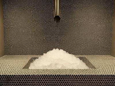 Espace spa moderne avec bain de vapeur et pyramide de mousse sur le banc.