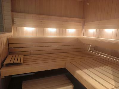 Sauna en bois avec longs bancs et éclairage mural lumineux.