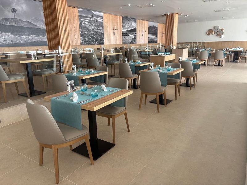 Ein modernes Restaurant mit Holzakzenten und türkisfarbenen Tischdekorationen.