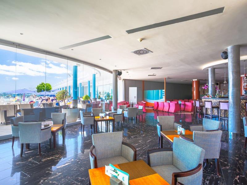 Moderner, heller Gastronomiebereich mit bequemen Sesseln, Tischen und Blick auf die Terrasse.