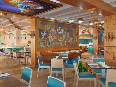 Modern eingerichteter Speisesaal mit bunten Stühlen und dekorativer Wandkunst.