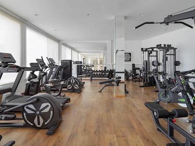 Moderner Fitnessraum mit Holzboden und umfassender Ausstattung in einem Hotel.