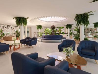 Modernes Hotel-Foyer mit blauen Sesseln, Pflanzen und rundem Oberlicht.