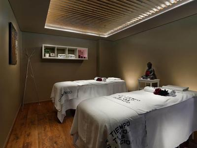 Ruhiger Wellnessraum mit zwei Massageliegen, gedämpfter Beleuchtung und Holzboden.