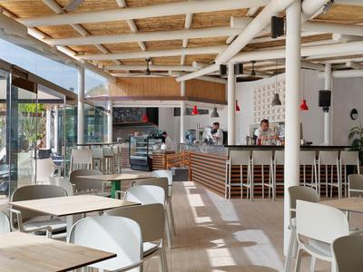 Modernes Café mit Holzbalkendecke, weißen Möbeln und offenem Tresenbereich.