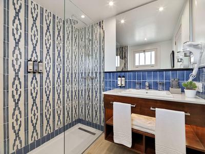 Modern bathroom with patterned glass wall and blue tiled sink area.