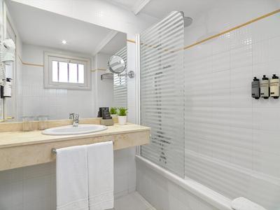 Modernes Badezimmer mit Dusche, Waschbecken und Handtüchern in einem Hotel.