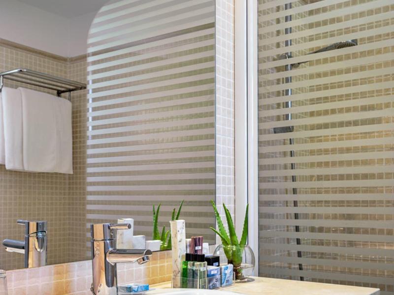 Bagno dell'hotel moderno con lavabo, rubinetto, articoli da toilette e piante sul piano.