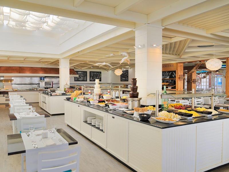 Buffet moderno e luminoso in hotel con vari cibi per la colazione e area pranzo organizzata.