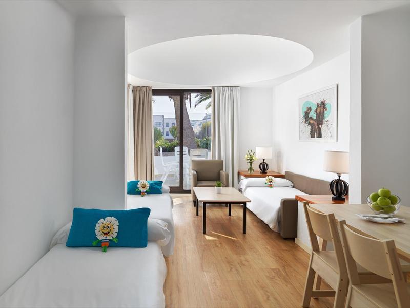 Camera d'hotel luminosa e moderna con due letti, pavimento in legno e grande finestra con balcone.