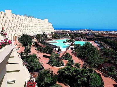 Große Hotelanlage mit Pool, Palmen, Wegen und Blick auf das blaue Meer im Hintergrund.
