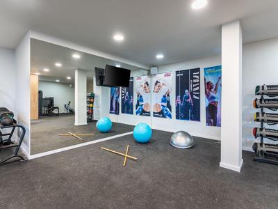 Gimnasio moderno con pelotas de ejercicio, pesas y pared con espejo en tonos neutros.