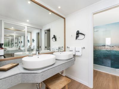 Moderne badkamer met dubbele wastafels, grote spiegel en toegang tot badkuip.