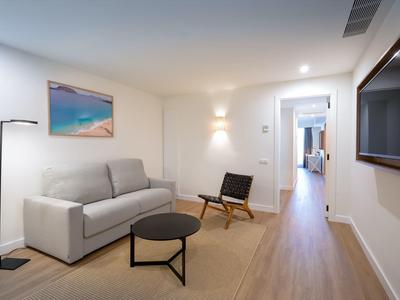 Modern ingerichte woonkamer met grijze bank, zwarte stoel en flatscreen-tv aan de muur.