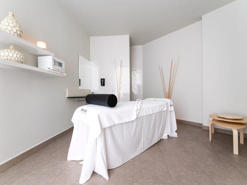 Heldere, schone wellnessruimte met massagetafel en minimale inrichting.