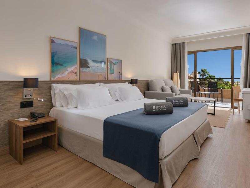 Moderne hotelkamer met groot bed, balkon en uitzicht op zee.