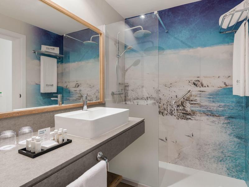 Moderne badkamer met rechthoekige wastafel, grote spiegel en douche met zee-thema.