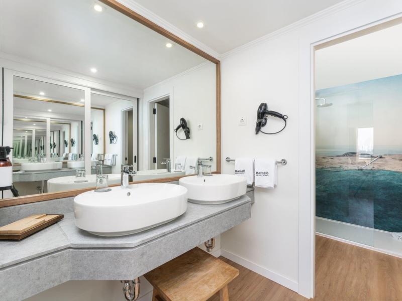 Moderne badkamer met dubbele wastafels, grote spiegel en toegang tot badkuip.