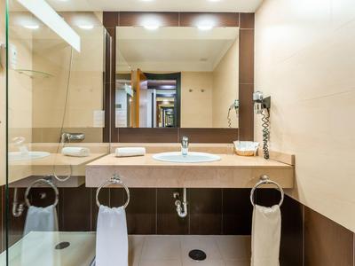 Moderner Badezimmer-Waschplatz mit rechteckigem Spiegel, Doppelwaschbecken und weißen Handtüchern.
