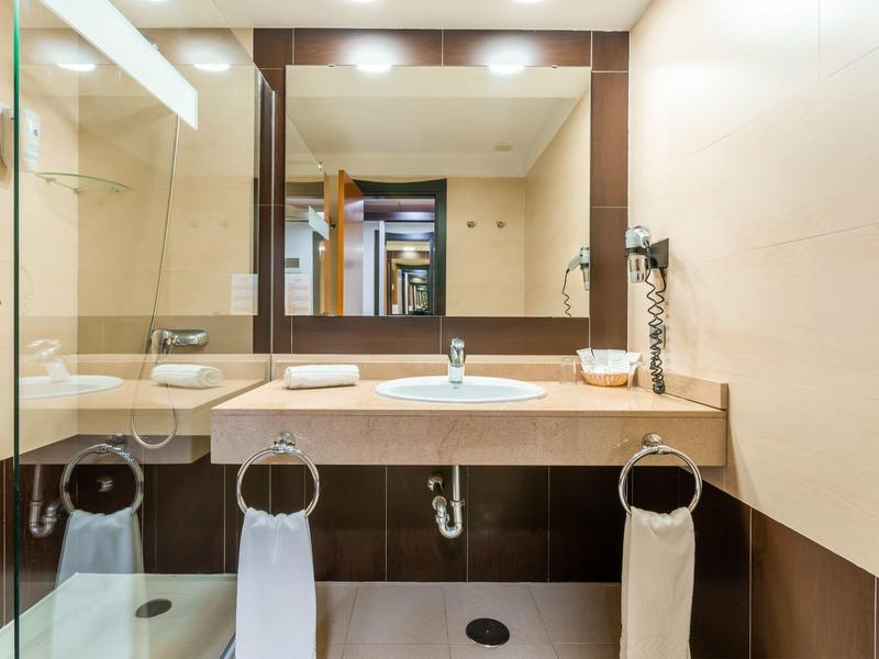 Bagno moderno con grande specchio, lavabo, piano e asciugamani appesi a anelli.