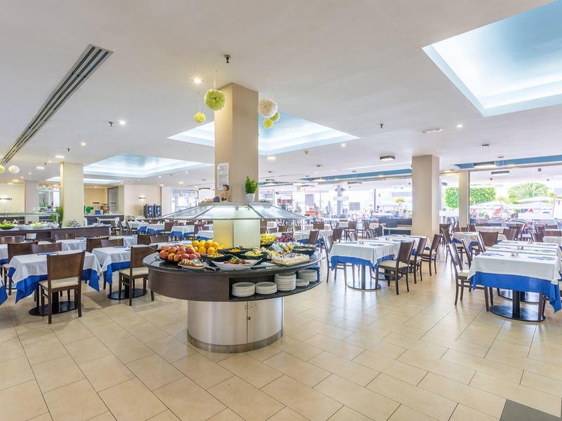 Ampia e luminosa sala da pranzo dell'hotel con buffet e molti tavoli coperti da tovaglie blu e bianche.