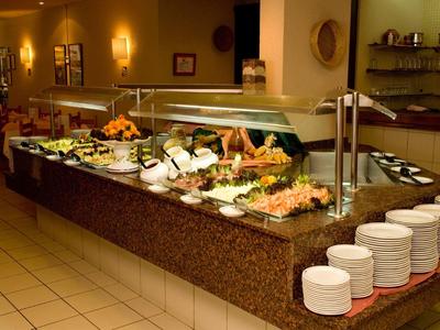 Buffet mit warmen und kalten Speisen, Tellern und dekorativen Elementen in einem hellen Raum.