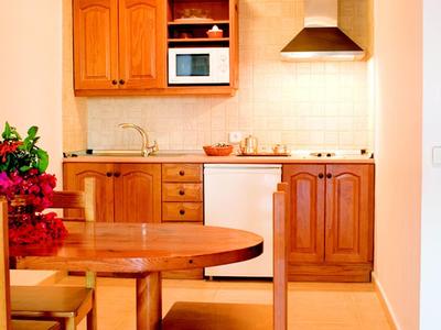 Kleine Küche mit Holzmöbeln, rundem Esstisch, zwei Stühlen und moderner Küchenausstattung.
