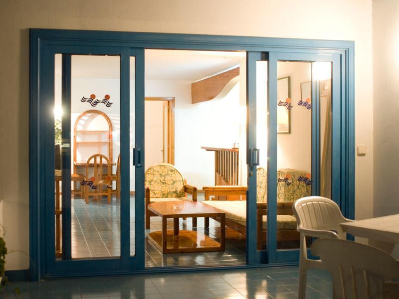 Vista attraverso porte scorrevoli blu su un soggiorno accogliente con divano e tavolo.