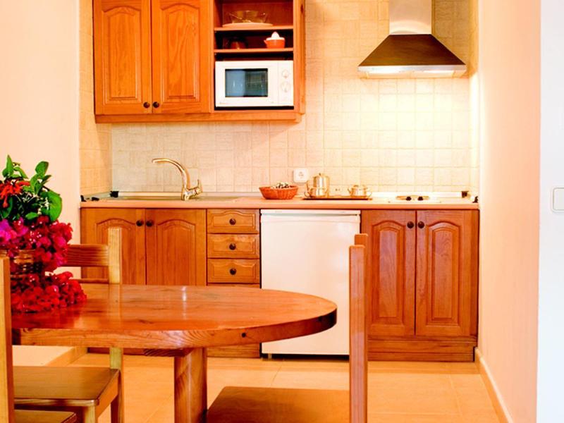 Piccola cucina con armadi in legno e tavolo rotondo con sedie.