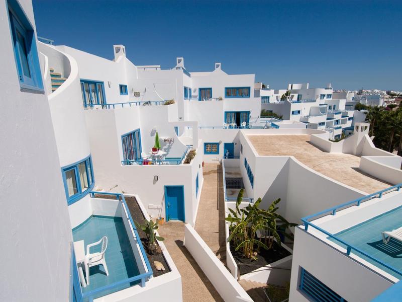 Edifici bianchi con finestre e porte blu sotto un cielo terso.