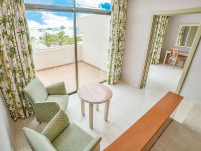 Soggiorno luminoso con due poltrone verdi, piccolo tavolo rotondo e vista sul balcone.