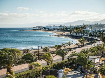 Paesaggio costiero con spiaggia, palme e hotel con tempo sereno.