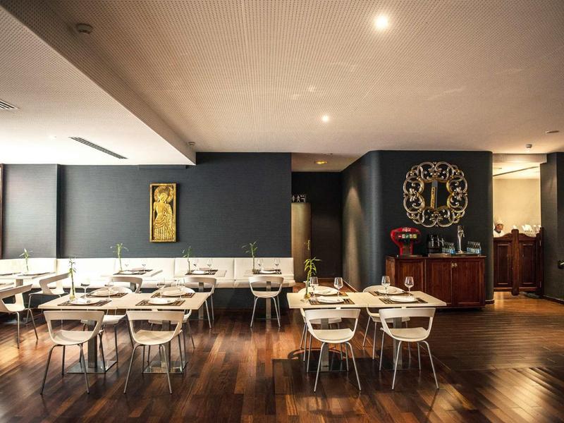 Sala da pranzo moderna con sedie bianche, pavimento in legno e pareti scure.