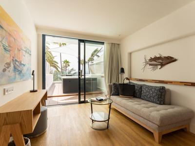 Helles Wohnzimmer mit Holzfußboden, grauem Sofa, großem Gemälde und Glas-Schiebetür zum Balkon.