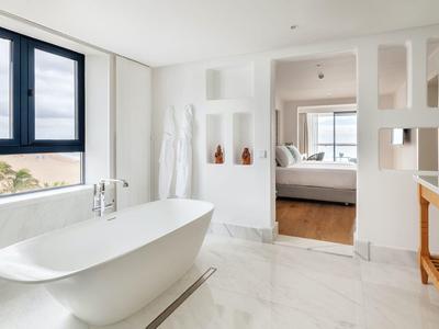 Modernes Badezimmer mit freistehender Badewanne, großen Fenstern und weißem Marmorboden.