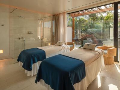 Bright spa room with two treatment beds and access to a garden area.
