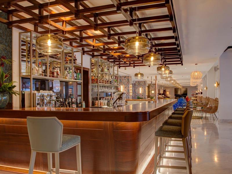Bar dell'hotel moderno con mobili in legno, luci eleganti e atmosfera accogliente.