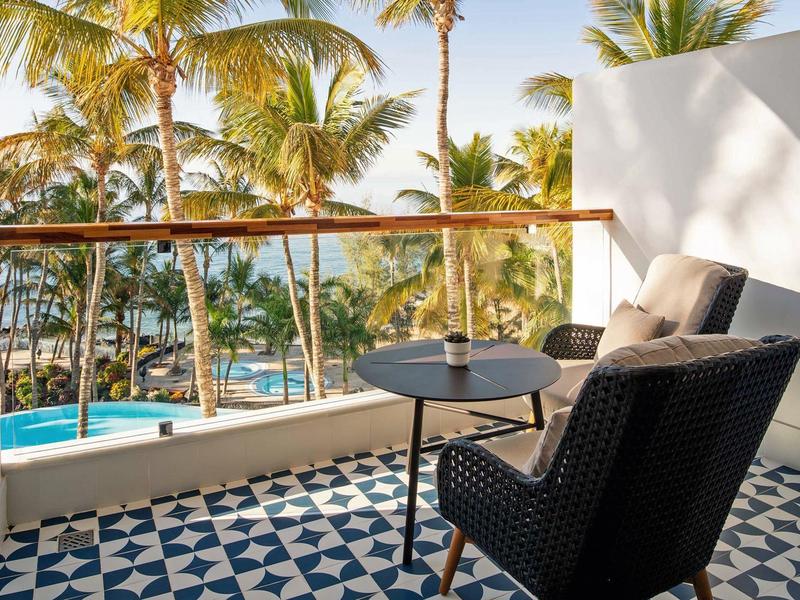 Terrazza con vista mare, poltrona comoda e tavolino in giornata soleggiata.