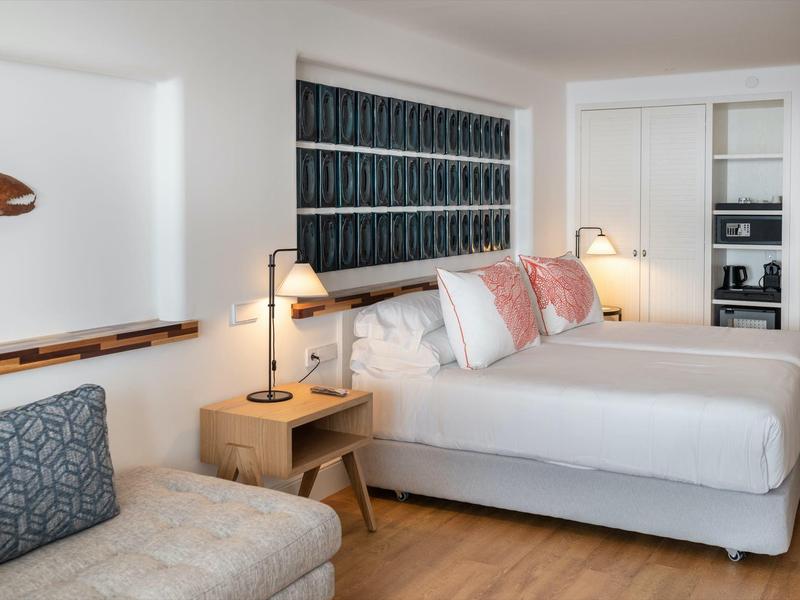 Camera d'hotel moderna con due letti, testiere decorate e comodini laterali.