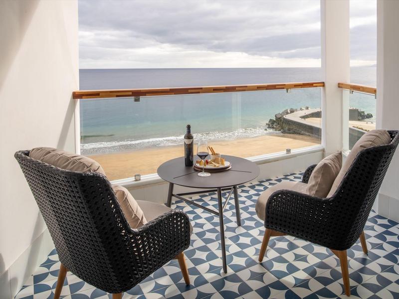 Balcone con due sedie e tavolo con vista mare in un hotel sulla spiaggia.
