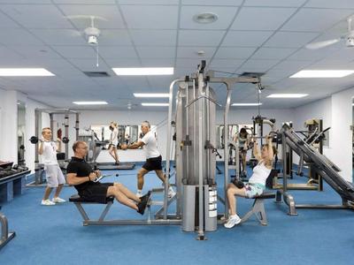 Moderne Turnhalle mit blauem Boden, mehreren Geräten und fünf Personen beim Training.