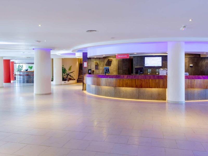 Ampia hall di hotel moderno con banco accoglienza circolare e illuminazione soffusa.