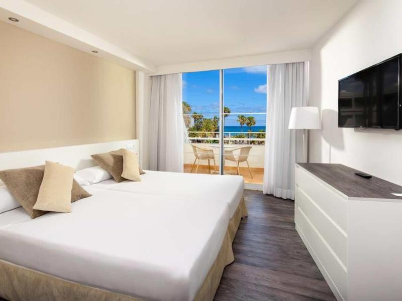 Camera d'hotel moderna con letto matrimoniale, balcone e vista sul mare.