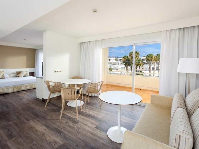 Soggiorno luminoso con divano, tavolo, sedie e accesso a terrazza con vista urbana.