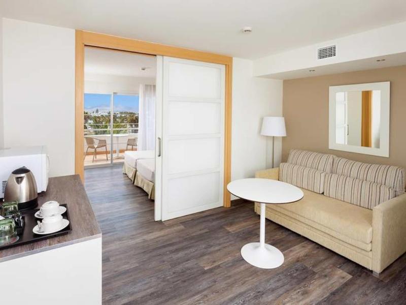 Soggiorno moderno con divano beige, tavolo bianco rotondo e vista sulla camera e terrazza.