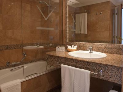 Modernes Badezimmer mit Marmorwaschtisch, Badewanne und Handtüchern in einem Hotel.