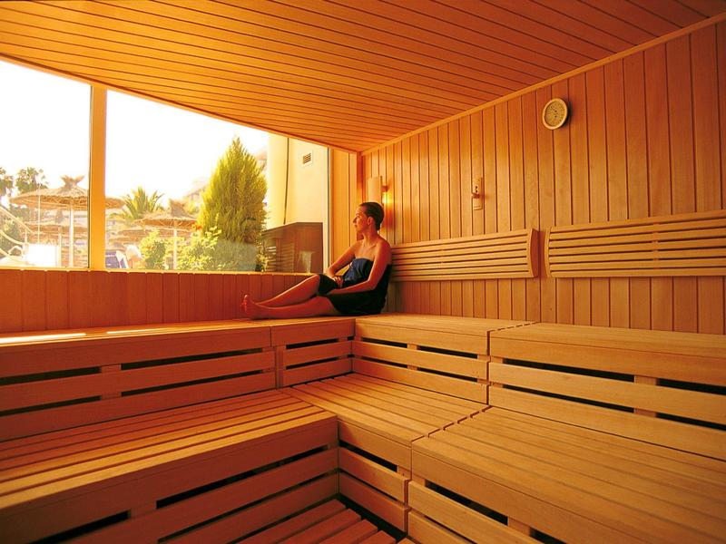 Donna che si rilassa in una sauna con ampia finestra che affaccia sul verde.